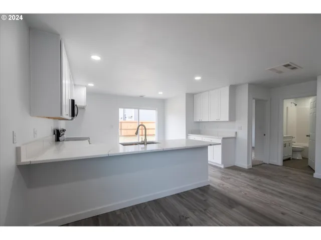 a open kitchen with kitchen island a sink dishwasher a stove and a refrigerator with wooden floor