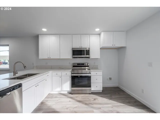 a kitchen with granite countertop white cabinets and stainless steel appliances
