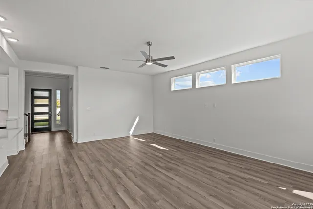 a view of an empty room with window and wooden floor