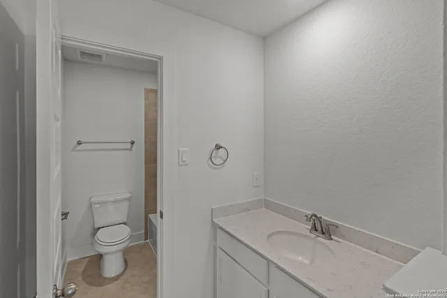 a bathroom with a granite countertop toilet a sink and a mirror