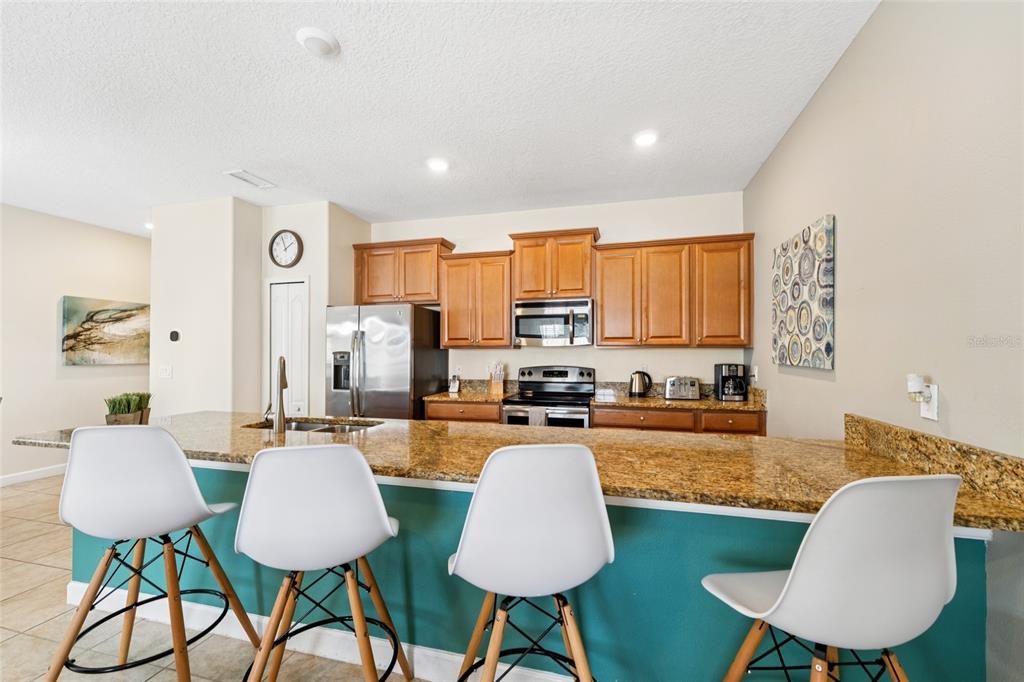 4841 Clock Tower Drive Kissimmee, FL 34746 - Photo 12 of 36 a kitchen with sink refrigerator and dining table