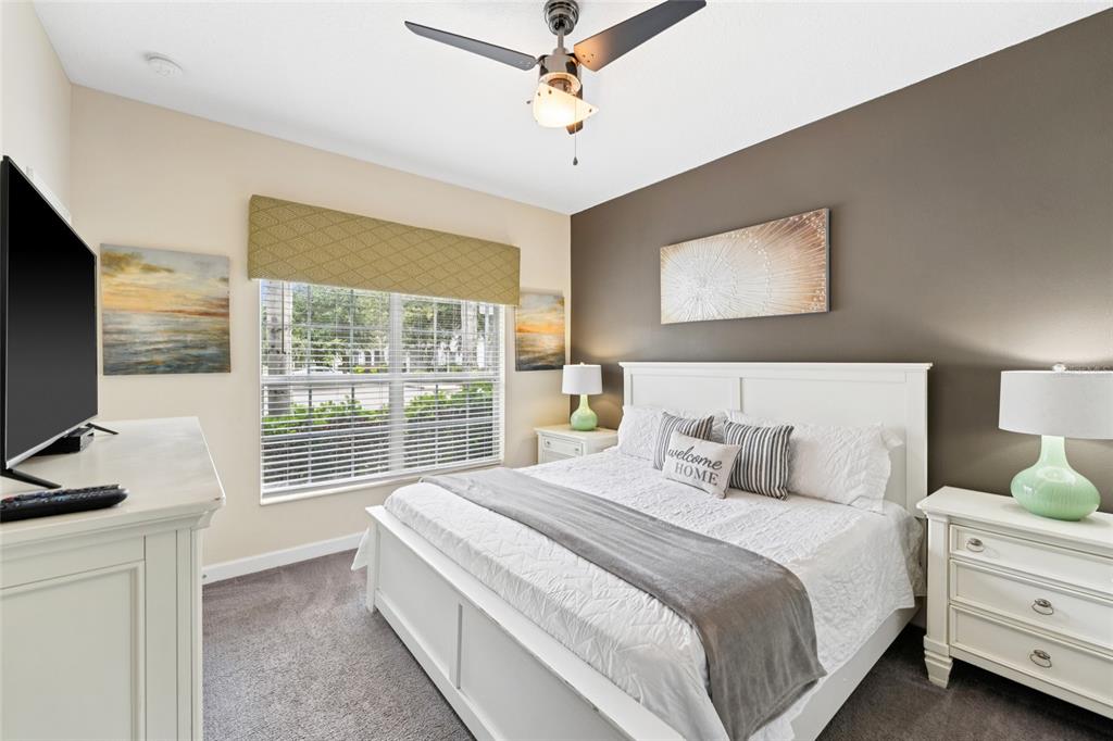 4841 Clock Tower Drive Kissimmee, FL 34746 - Photo 14 of 36 a bedroom with a balcony a bed and a flat tv screen on dresser