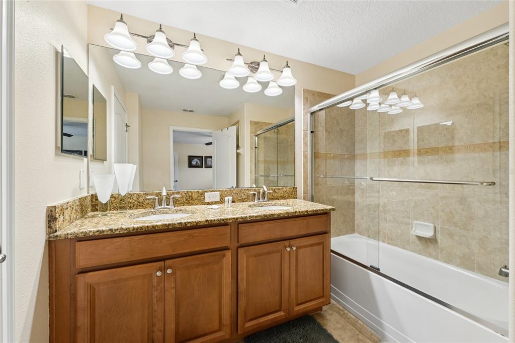 4841 Clock Tower Drive Kissimmee, FL 34746 - Photo 18 of 36 a bathroom with a granite countertop sink a large mirror and a shower