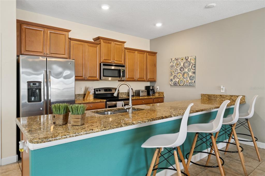 4841 Clock Tower Drive Kissimmee, FL 34746 - Photo 5 of 36 a kitchen with stainless steel appliances granite countertop a table chairs in it and wooden floors