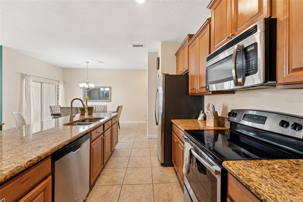 4841 Clock Tower Drive Kissimmee, FL 34746 - Photo 6 of 36 a kitchen with granite countertop a sink stove and refrigerator