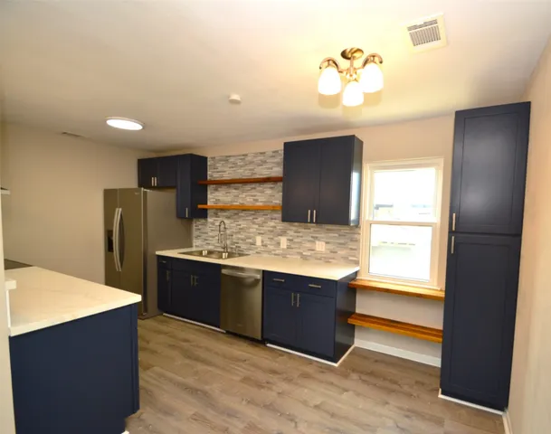 a view of kitchen with stainless steel appliances wooden cabinets and front door