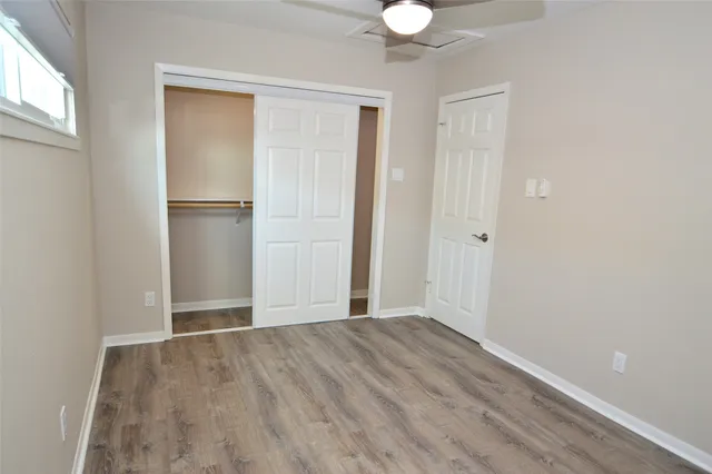 a view of an empty room with window and wooden floor