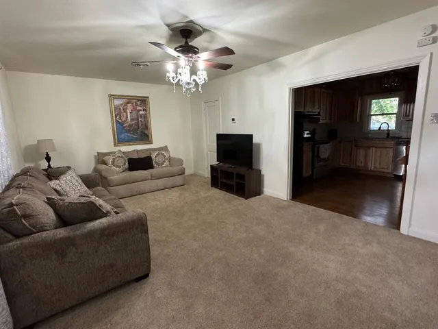 a living room with furniture a chandelier and a flat screen tv