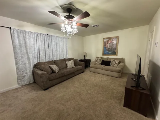 a living room with furniture a chandelier and a flat screen tv