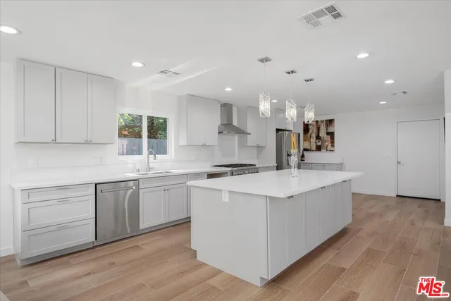 a kitchen with kitchen island a sink and a stove top oven with wooden floor