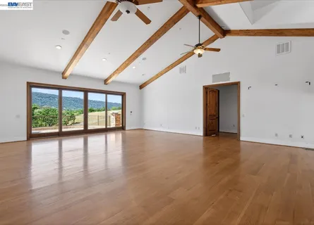 a view of an empty room with wooden floor fireplace and a window
