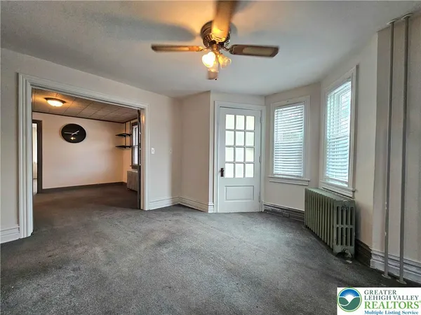 an empty room with windows and fan