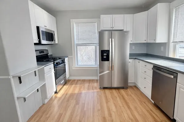 a kitchen with white cabinets stainless steel appliances and wooden floor
