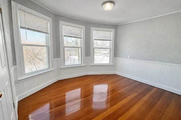 an empty room with wooden floor and windows
