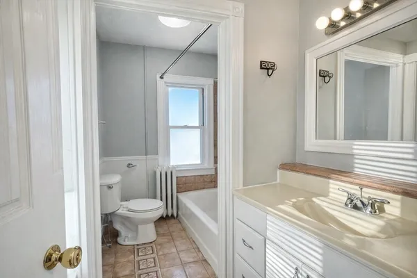 a bathroom with a granite countertop sink mirror vanity and toilet