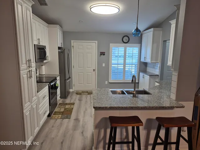 a kitchen with kitchen island granite countertop a table chairs in it and wooden floors