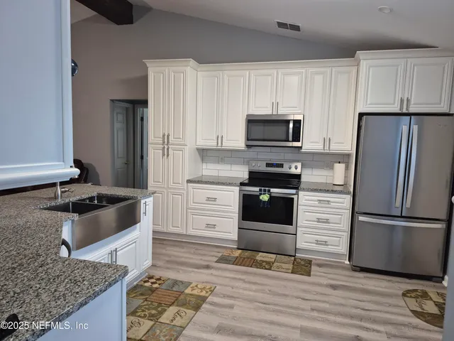 a kitchen with granite countertop a refrigerator stove and microwave
