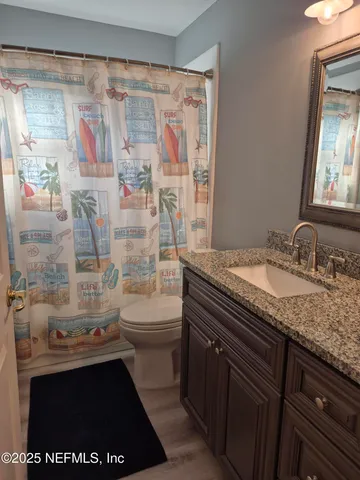 a bathroom with a granite countertop sink a toilet and shower