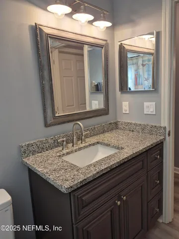 a bathroom with a granite countertop sink and a mirror
