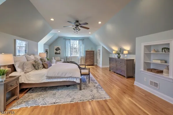 a spacious bedroom with a large bed a chandelier and dresser