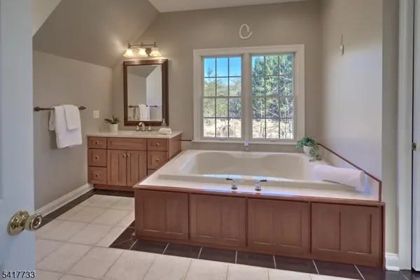 a bathroom with a tub a sink and mirror