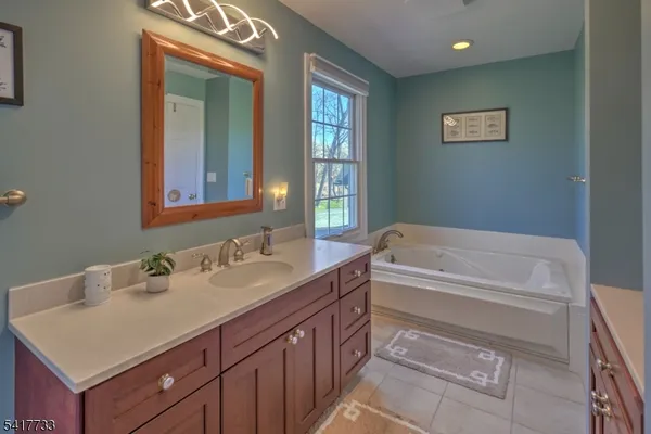 a bathroom with a tub sink and mirror