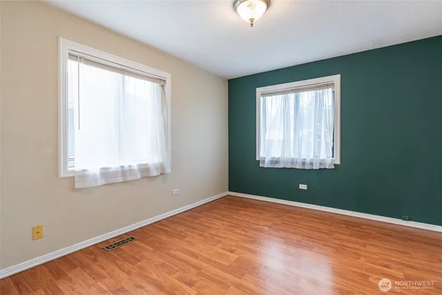 an empty room with a window and wooden floor