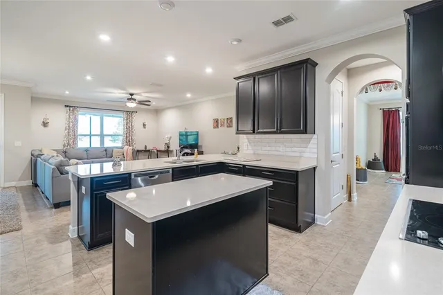 a living room with furniture kitchen view and a chandelier