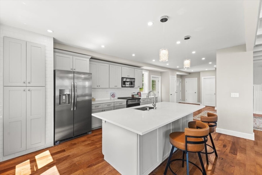 1366 Gardners Neck Road Swansea, MA 02777 - Photo 20 of 35 a kitchen with stainless steel appliances kitchen island granite countertop a refrigerator a stove a sink a dining table and chairs with wooden floor