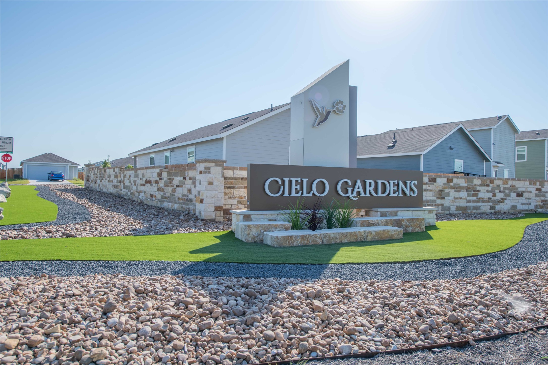 309 Marty Allen Loop Jarrell, TX 76537 - Photo 29 of 33 Community entrance signage featuring "Cielo Gardens" lettering, a decorative hummingbird motif, and stone-clad base