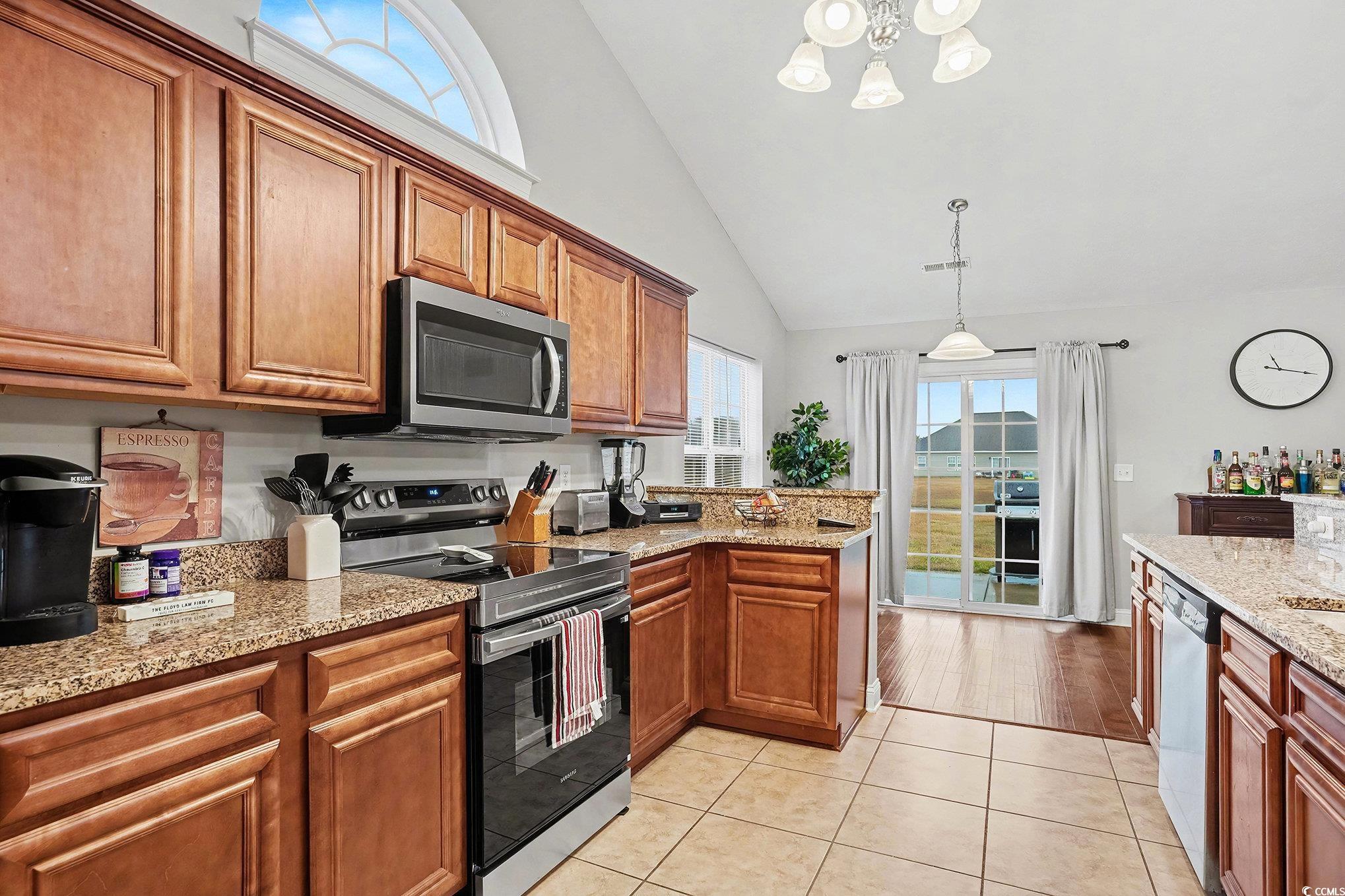 216 Camrose Way Myrtle Beach, SC 29588 - Photo 12 of 32 Kitchen with healthy amount of natural light, stainless steel appliances, a peninsula, brown cabinets, and high vaulted ceiling