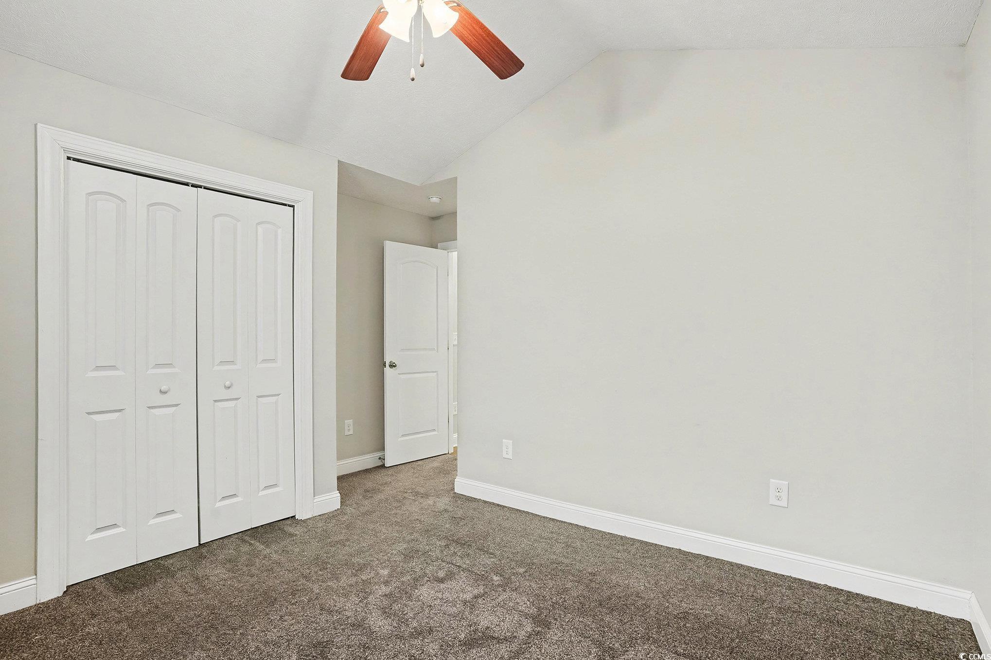 216 Camrose Way Myrtle Beach, SC 29588 - Photo 21 of 32 Unfurnished bedroom with dark carpet, a closet, vaulted ceiling, and ceiling fan