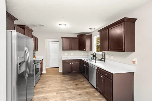 a large kitchen with a sink refrigerator and cabinets
