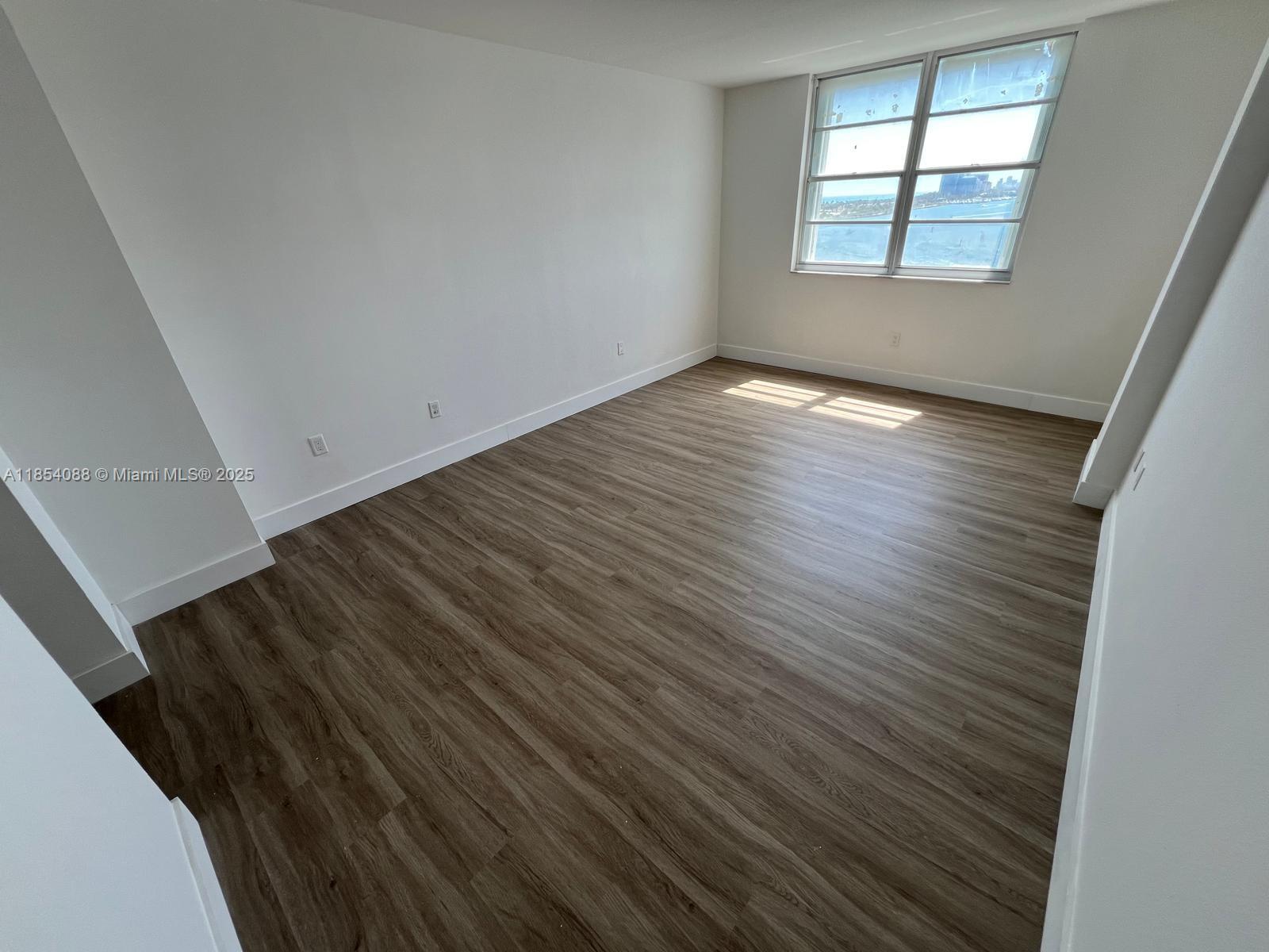 500 Bayview Drive, Unit 1120 Sunny Isles Beach, FL 33160 - Photo 22 of 46 a view of an empty room with wooden floor and a window