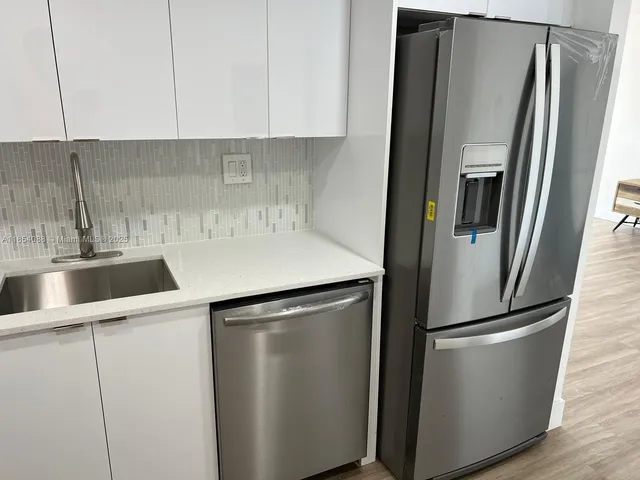 a kitchen with a refrigerator sink and cabinets