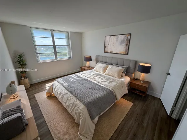 a view of an empty room with wooden floor and window