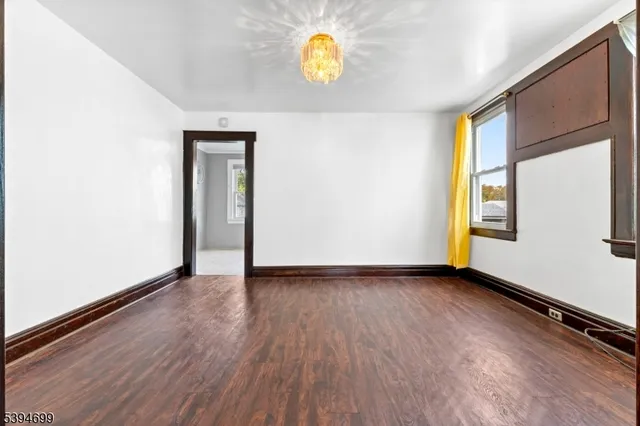 a view of an empty room with window and wooden floor