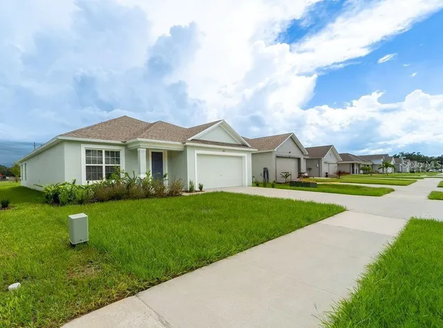 a view of a house with a yard and large trees