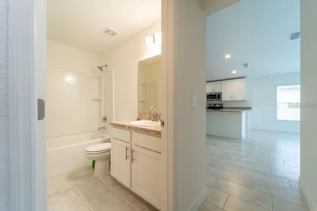 a bathroom with a granite countertop sink a toilet and shower