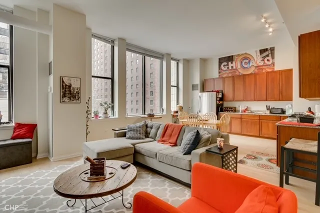 a living room with furniture kitchen view and a window