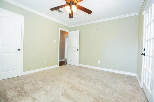 an empty room with a chandelier fan and windows