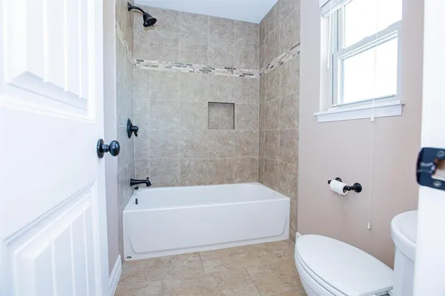 a bath room with a toilet a bath tub and a shower