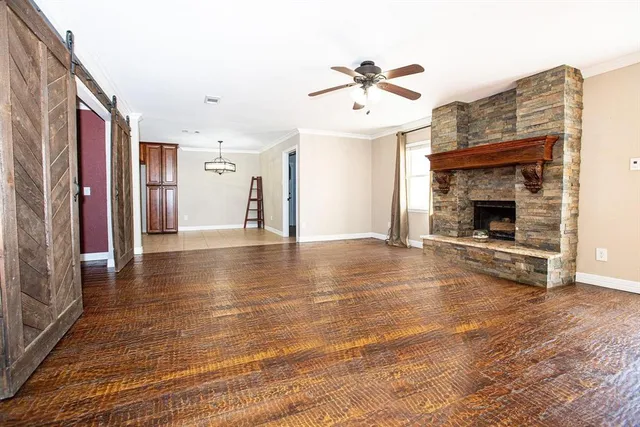 a view of an empty room with wooden floor fireplace and a window