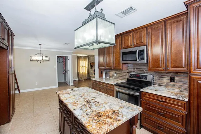a kitchen with stainless steel appliances granite countertop wooden cabinets a stove top oven a sink and dishwasher