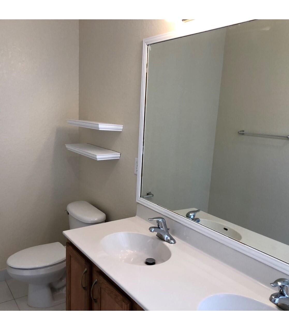 2031 Southeast Oldsmar Road Port St. Lucie, FL 34952 - Photo 11 of 14 a bathroom with a sink toilet and mirror