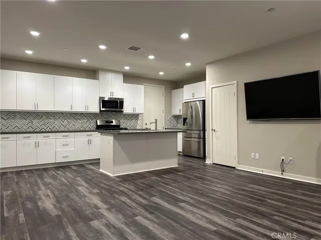 a kitchen with stainless steel appliances a sink a stove a refrigerator and cabinets