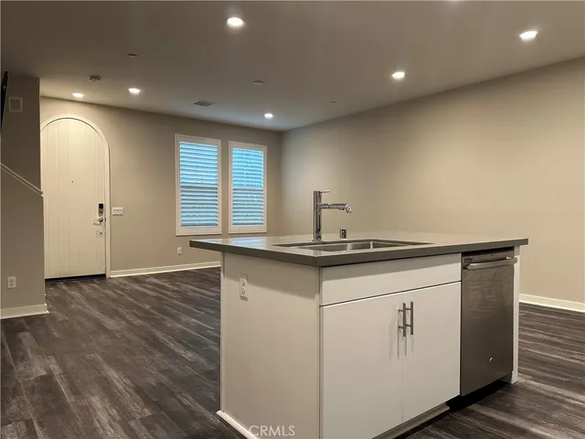 a kitchen with stainless steel appliances wooden floor and a refrigerator