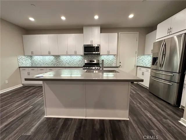 a large kitchen with kitchen island granite countertop a stove top oven a sink and a white cabinets