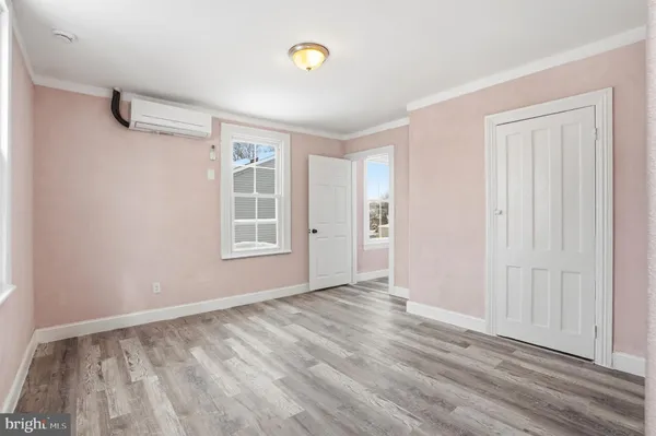a view of an empty room with window and wooden floor
