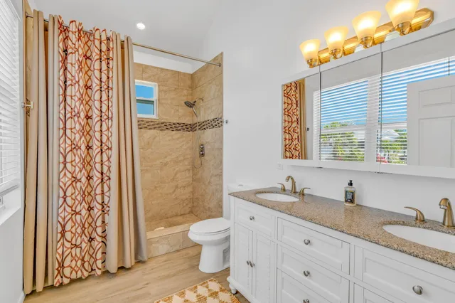 a bathroom with a granite countertop sink toilet a mirror a vanity and shower